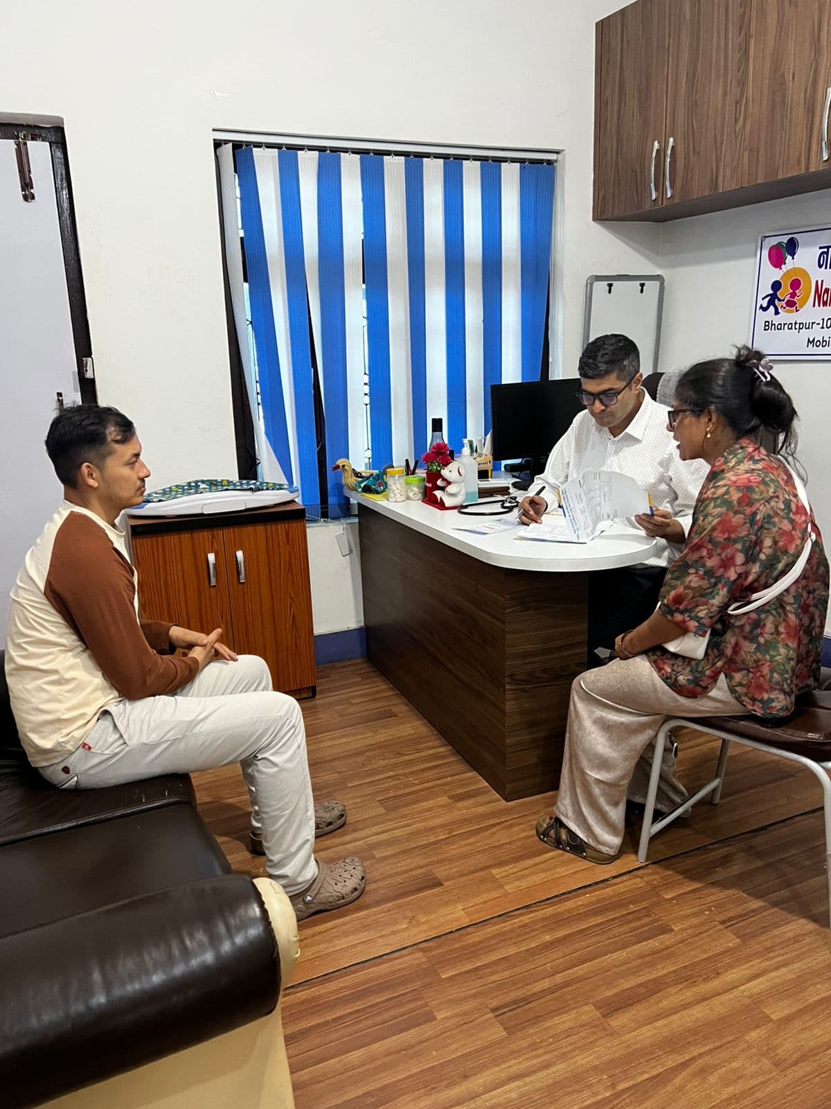 Dr. Yograj Sharma reviewing child health records with parents